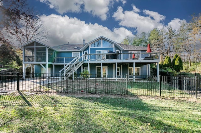 rear view of house with a sunroom, a yard, and a deck