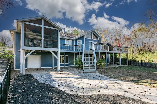 back of house with a sunroom, a deck, and a garage