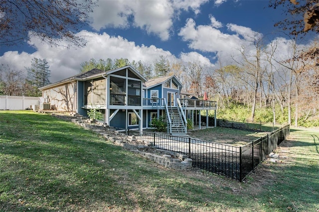 back of property featuring a yard, a deck, and a sunroom