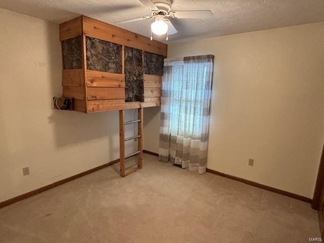 unfurnished bedroom with light carpet, a textured ceiling, and ceiling fan