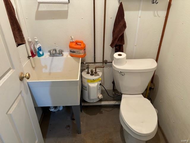 bathroom with concrete flooring, toilet, and sink