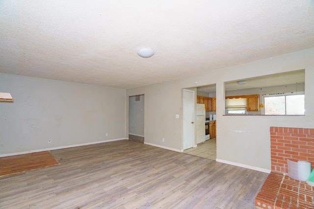 unfurnished living room with a textured ceiling and light hardwood / wood-style flooring