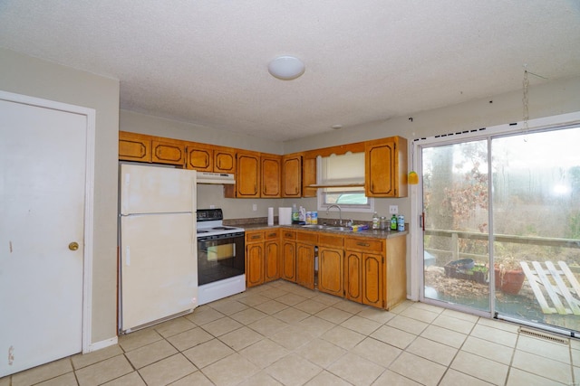 kitchen featuring a textured ceiling, white appliances, sink, and light tile patterned floors