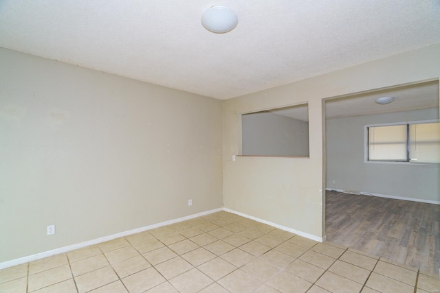 empty room with light hardwood / wood-style floors and a textured ceiling