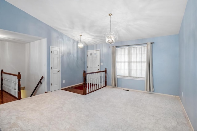 carpeted empty room featuring lofted ceiling and an inviting chandelier