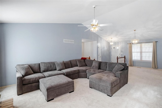 carpeted living room with ceiling fan with notable chandelier and vaulted ceiling