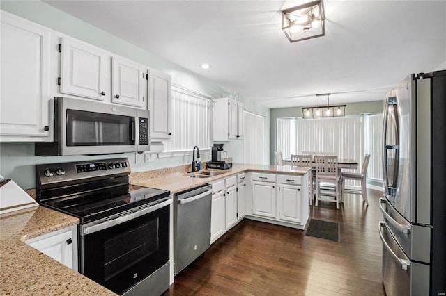 kitchen featuring white cabinetry, sink, stainless steel appliances, dark hardwood / wood-style flooring, and decorative light fixtures