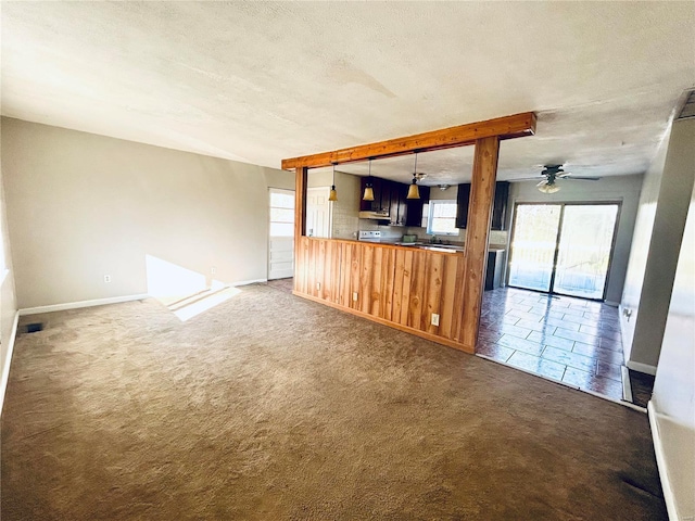 unfurnished living room featuring a ceiling fan, baseboards, carpet floors, and a textured ceiling