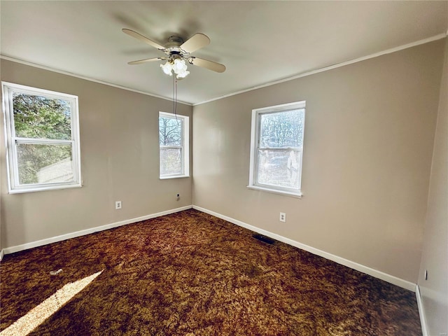 unfurnished room with ceiling fan, baseboards, dark colored carpet, and ornamental molding