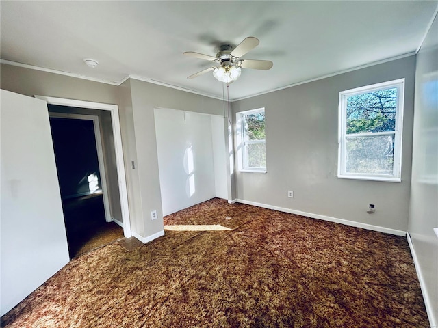 unfurnished bedroom with ornamental molding, a closet, dark colored carpet, baseboards, and ceiling fan