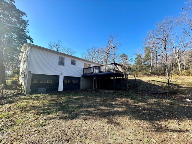 back of property with an attached garage, driveway, and a wooden deck