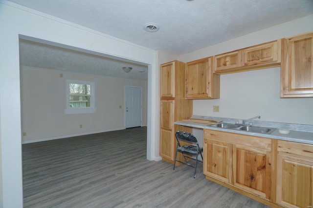 kitchen featuring a textured ceiling, light brown cabinets, sink, and light hardwood / wood-style flooring