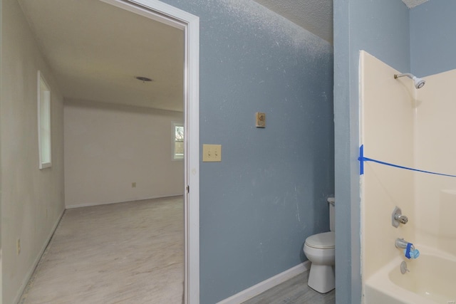 bathroom with shower / tub combination, toilet, a textured ceiling, and hardwood / wood-style flooring