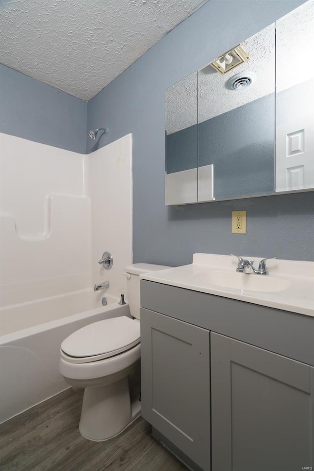 full bathroom with hardwood / wood-style floors, vanity, toilet, a textured ceiling, and tub / shower combination