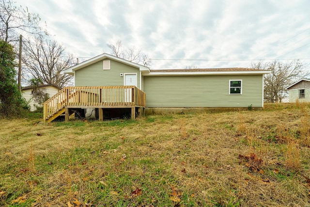 rear view of property featuring a deck and a lawn