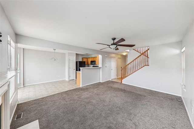 unfurnished living room featuring light colored carpet and ceiling fan with notable chandelier