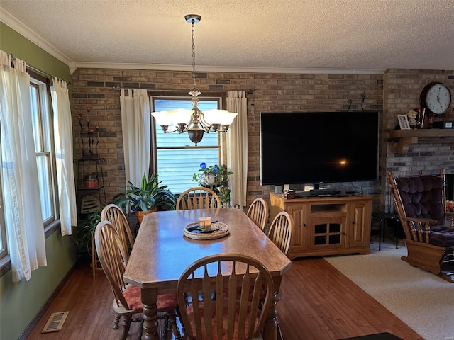 dining area featuring crown molding, an inviting chandelier, a textured ceiling, and hardwood / wood-style flooring