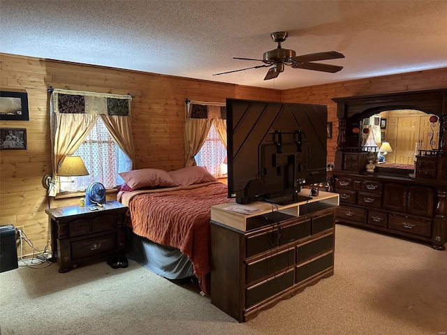 bedroom with wood walls, ceiling fan, light carpet, and a textured ceiling