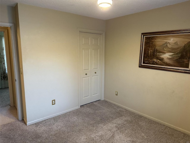 unfurnished bedroom with light carpet, a textured ceiling, and a closet