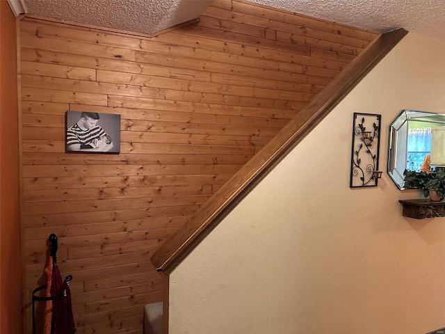 stairs with wood walls and a textured ceiling