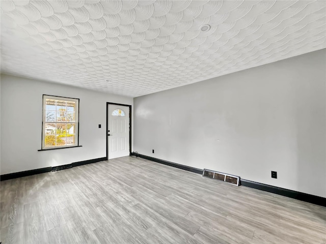 unfurnished room featuring a textured ceiling and light wood-type flooring