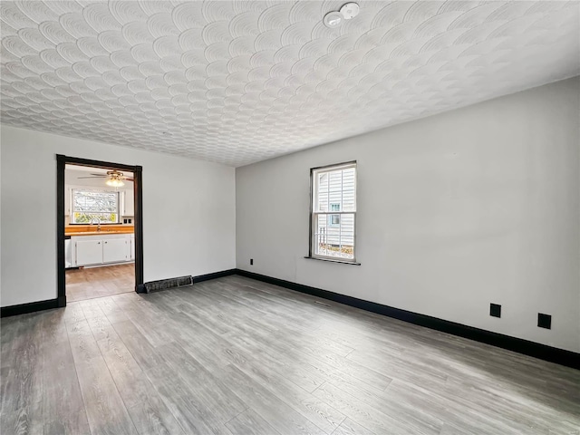 spare room with ceiling fan, sink, a textured ceiling, and light wood-type flooring