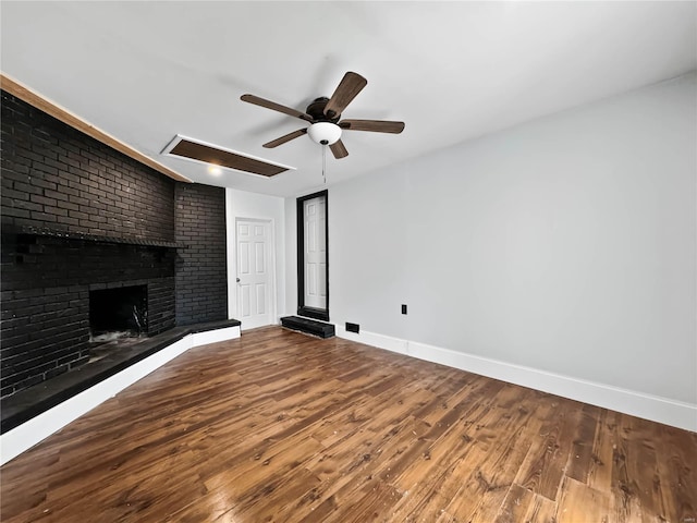 unfurnished living room with wood-type flooring, a brick fireplace, and ceiling fan