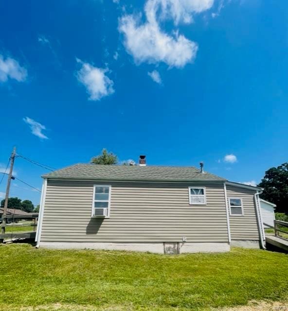 view of side of property featuring cooling unit and a yard