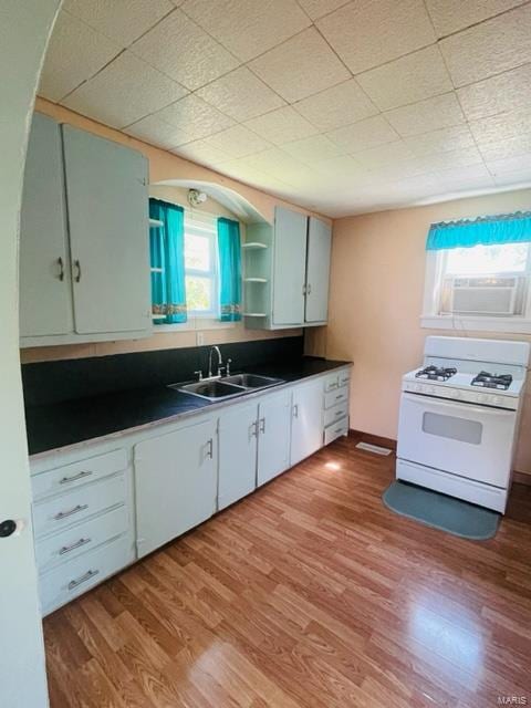 kitchen featuring white gas stove, light hardwood / wood-style floors, white cabinetry, and sink