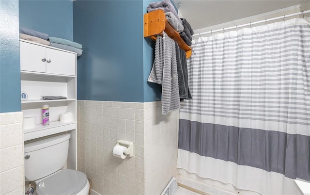 bathroom featuring tile walls and toilet