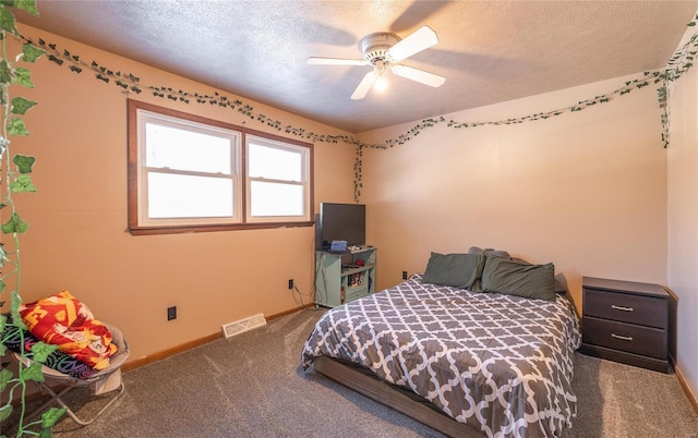 carpeted bedroom featuring ceiling fan and a textured ceiling