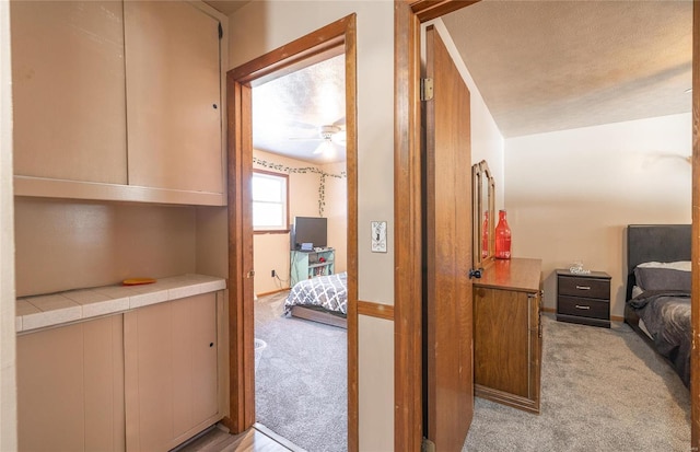 hallway featuring light colored carpet and a textured ceiling