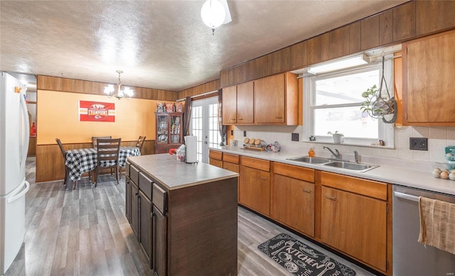 kitchen featuring dishwasher, sink, fridge, decorative light fixtures, and a kitchen island