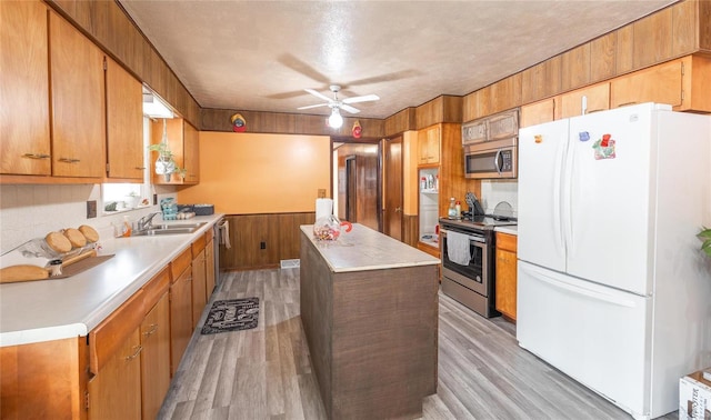 kitchen with appliances with stainless steel finishes, a textured ceiling, light hardwood / wood-style flooring, and sink