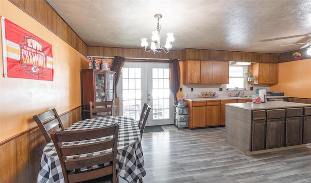 kitchen featuring wood walls, french doors, sink, a textured ceiling, and a kitchen island