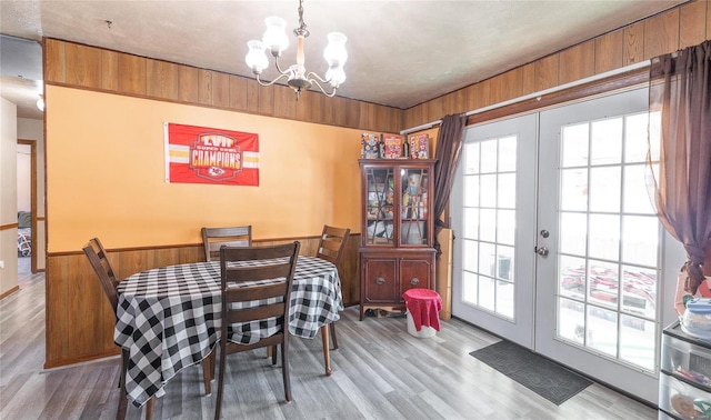 dining area with wood walls, french doors, a chandelier, and plenty of natural light