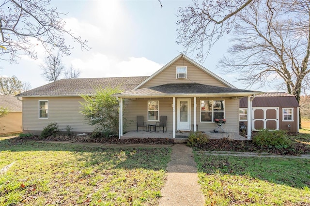 view of front facade featuring a porch, a storage shed, and a front yard