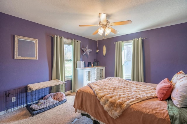 bedroom with a textured ceiling, carpet floors, multiple windows, and ceiling fan