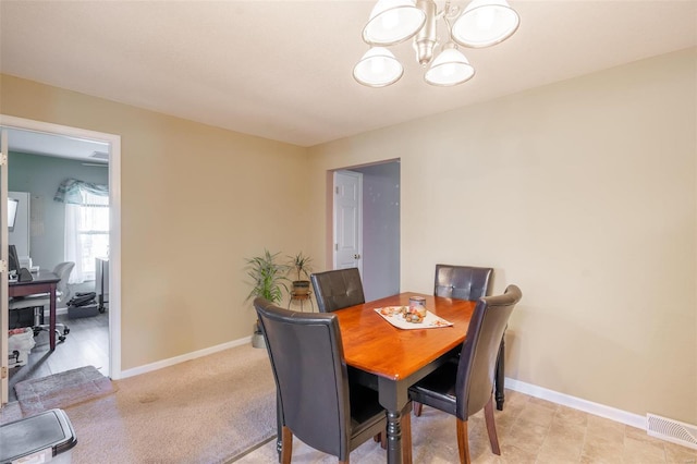 carpeted dining area with a chandelier