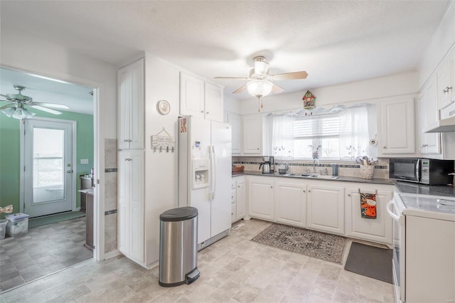 kitchen with white fridge with ice dispenser, white cabinets, and a healthy amount of sunlight