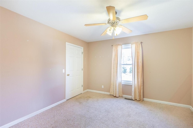 carpeted spare room with visible vents, ceiling fan, and baseboards