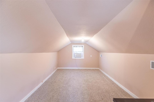 bonus room with a textured ceiling, vaulted ceiling, light carpet, and baseboards