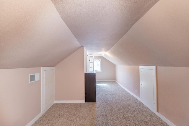 bonus room featuring visible vents, carpet flooring, vaulted ceiling, a textured ceiling, and baseboards