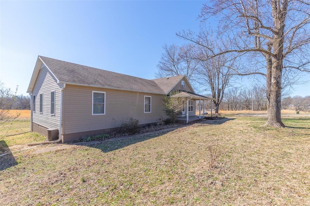 view of side of property featuring a shingled roof, a yard, and central air condition unit