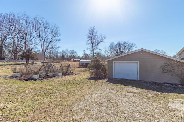 view of yard featuring dirt driveway, a detached garage, and an outbuilding