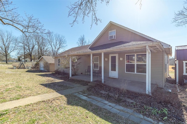 bungalow featuring an outbuilding, a porch, and a front yard