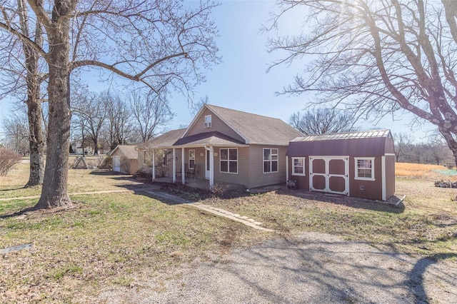 view of front of house featuring a porch, a shed, a front lawn, and an outdoor structure