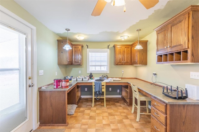 kitchen with brown cabinets, ceiling fan, decorative light fixtures, and built in study area