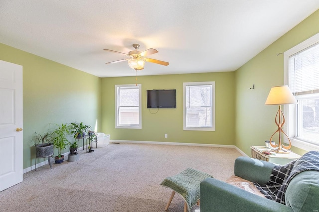 living area with carpet floors, plenty of natural light, baseboards, and ceiling fan