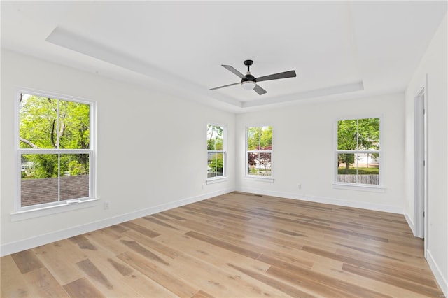 spare room with a raised ceiling, ceiling fan, and light hardwood / wood-style floors